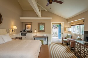 Habitación de hotel con una cama grande, un escritorio, una silla, un televisor y vistas al exterior.