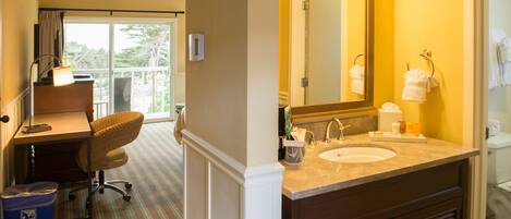 A hotel bathroom with a large mirror, two sinks, and a chair.