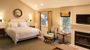 Camera d'albergo con un letto grande, una televisione, un caminetto e una finestra con tende.