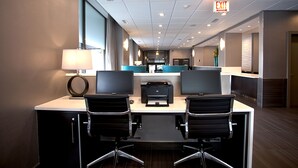A modern office space with two desks, each with a computer monitor, a printer, and a lamp. There is an exit sign on the ceiling. - Best Western River North Hotel (Chicago)