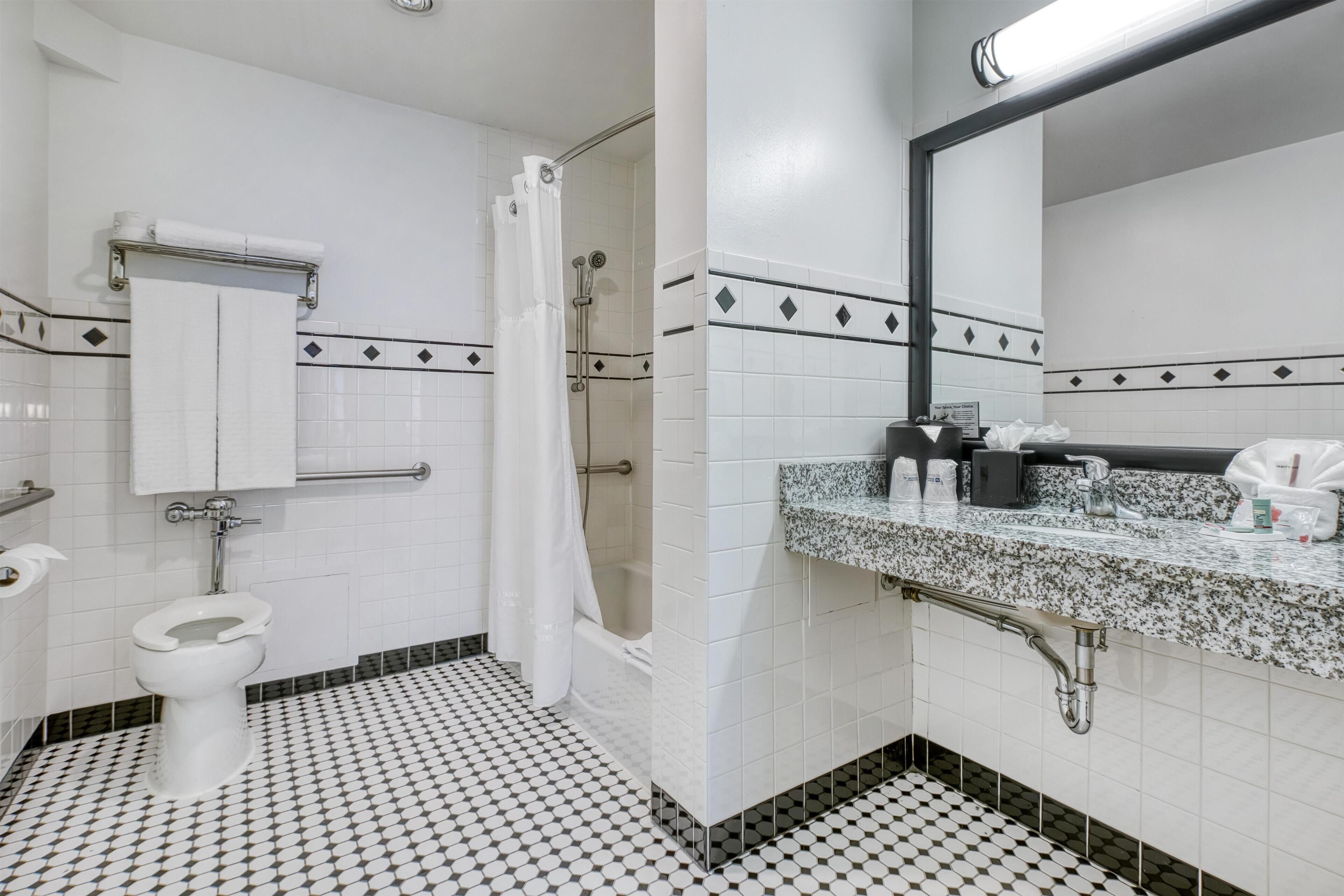 A bathroom with a toilet, shower, and sink.
