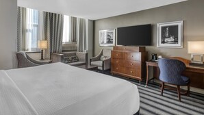 A hotel room with a large bed, two armchairs, a wooden dresser, a desk with a chair, a flat-screen TV, and framed pictures on the wall. - Best Western River North Hotel (Chicago)