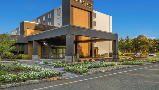 A modern Courtyard by Marriott hotel with a covered entrance, landscaped garden, and a parking area. - Courtyard by Marriott Rockaway Mount Arlington (Mount Arlington)