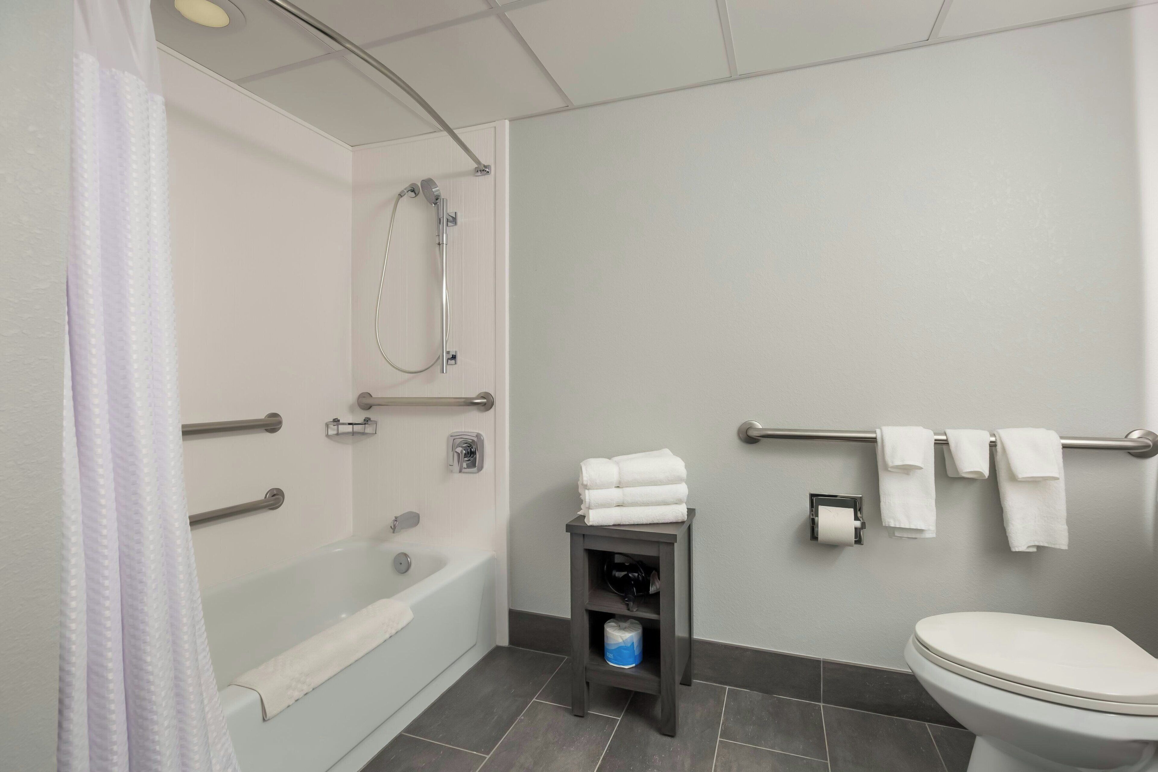 A modern bathroom with a bathtub, toilet, and shower.