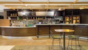 A modern bar area with a curved counter, two metal chairs, and a variety of bottles and glasses. - Courtyard by Marriott Rockaway Mount Arlington (Mount Arlington)