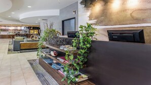 A modern reception area with a curved ceiling, a reception desk, and a seating area with a sofa and coffee table. - Courtyard by Marriott Rockaway Mount Arlington (Mount Arlington)
