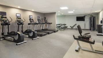 Une salle de sport équipée de tapis de course, d’haltères et d’appareils de musculation.