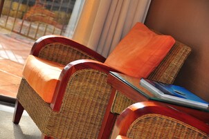 A wicker chair with a cushion and a book on a table.