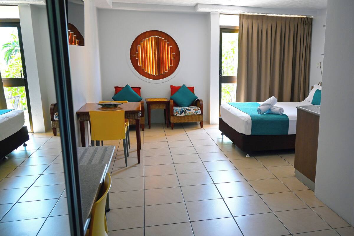 A hotel room with a bed, a desk, two chairs, a round wall decoration, and a view of the outdoors.
