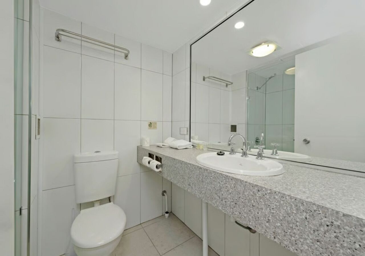 A modern bathroom with a toilet, sink, and mirror.