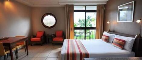 Una habitación de hotel con una cama, una mesa de comedor, una silla y una mesita.