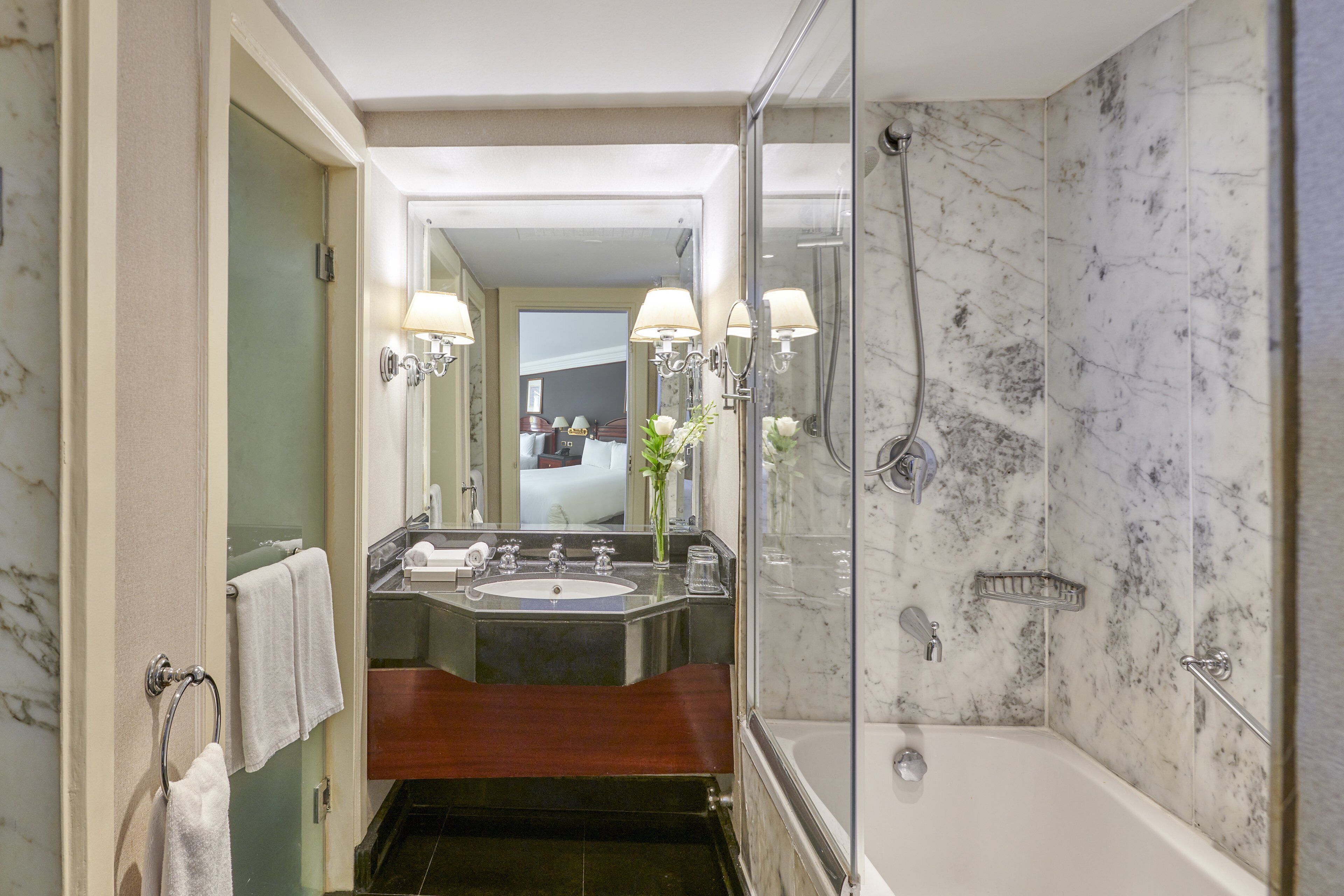 A modern bathroom with a glass-enclosed shower, a vanity with a sink and mirror, and a bathtub.