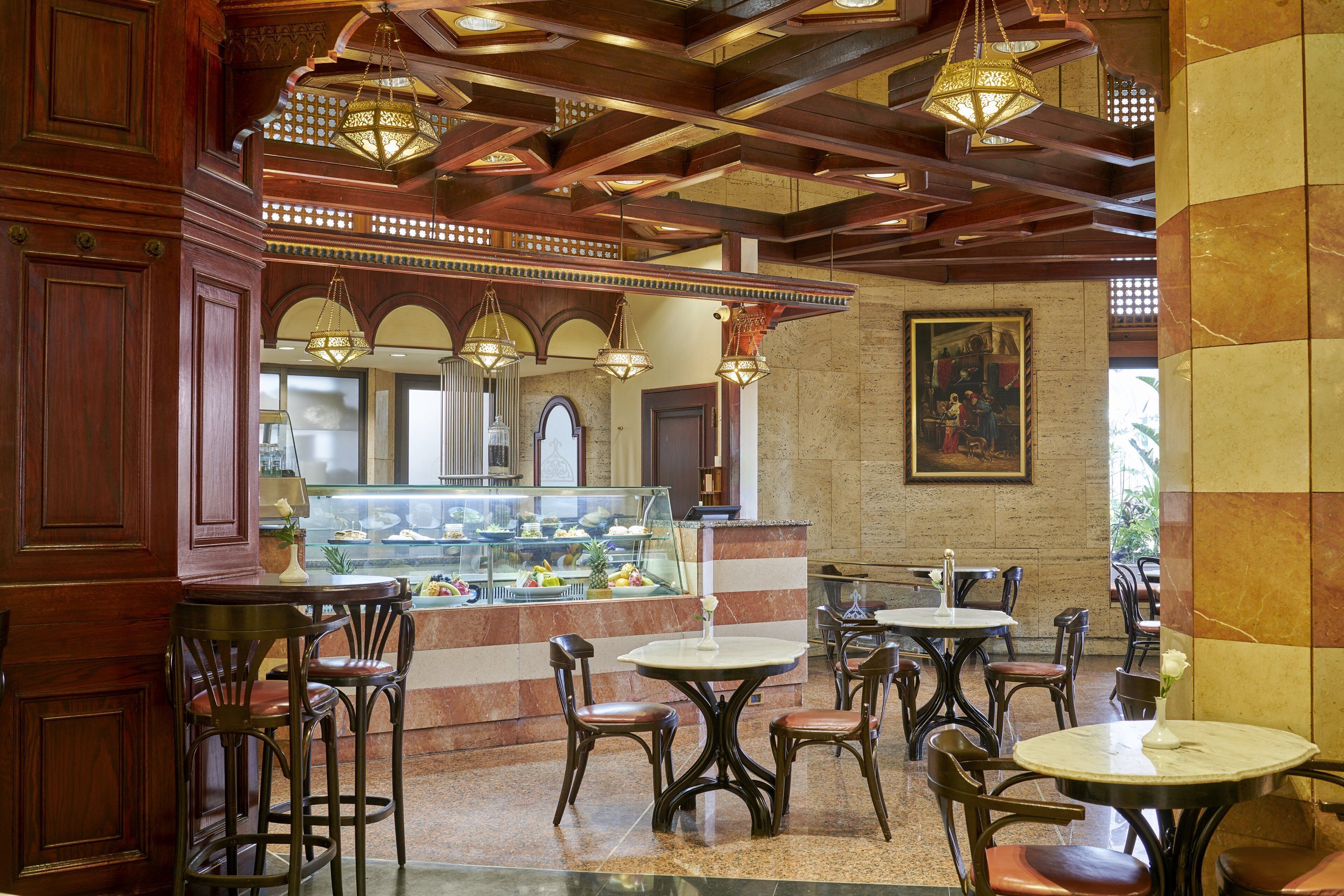 A restaurant with wooden furniture, a glass display case with food, and hanging lights.