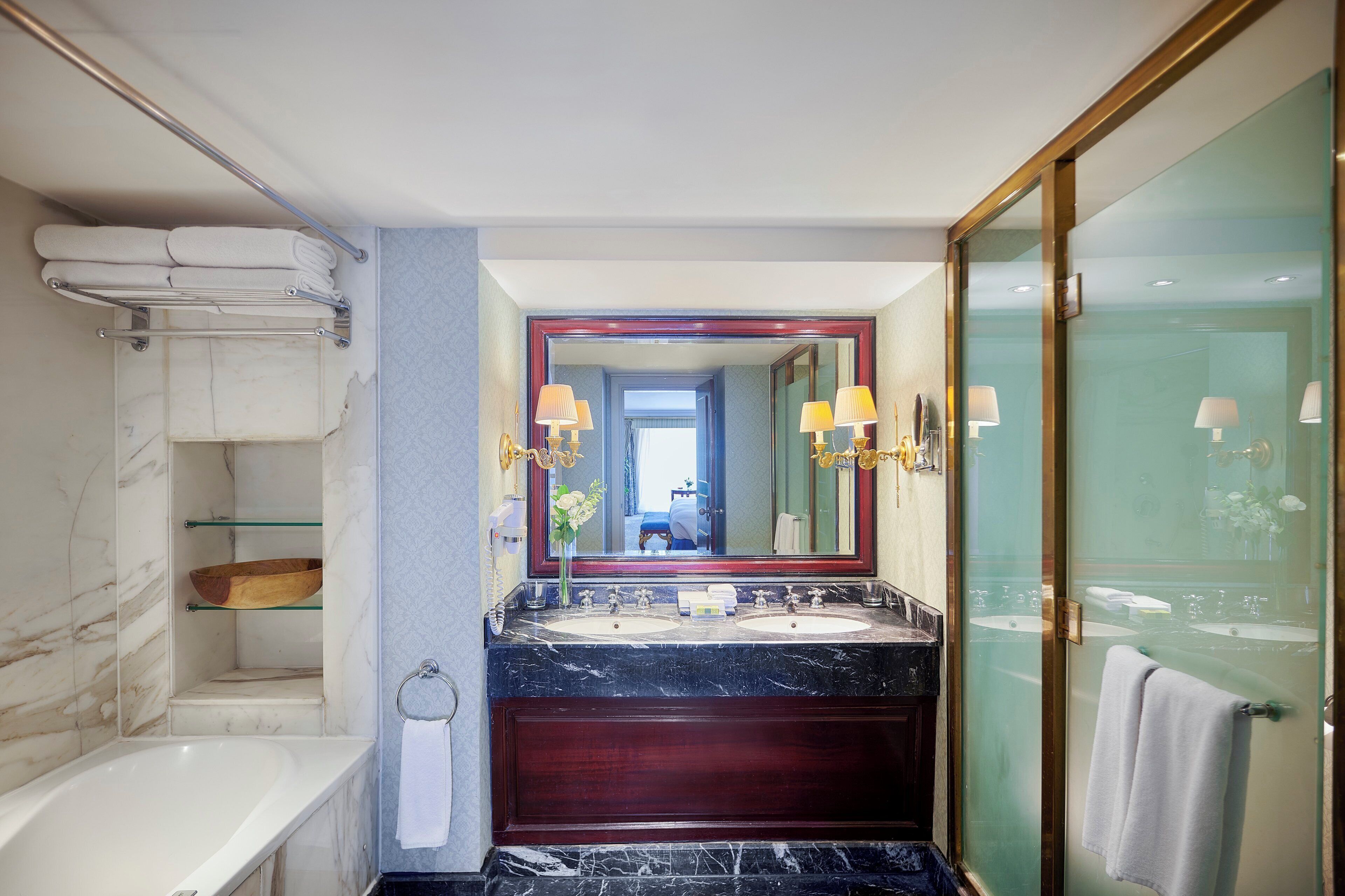 A modern bathroom with a marble sink, a bathtub, and a glass-enclosed shower.