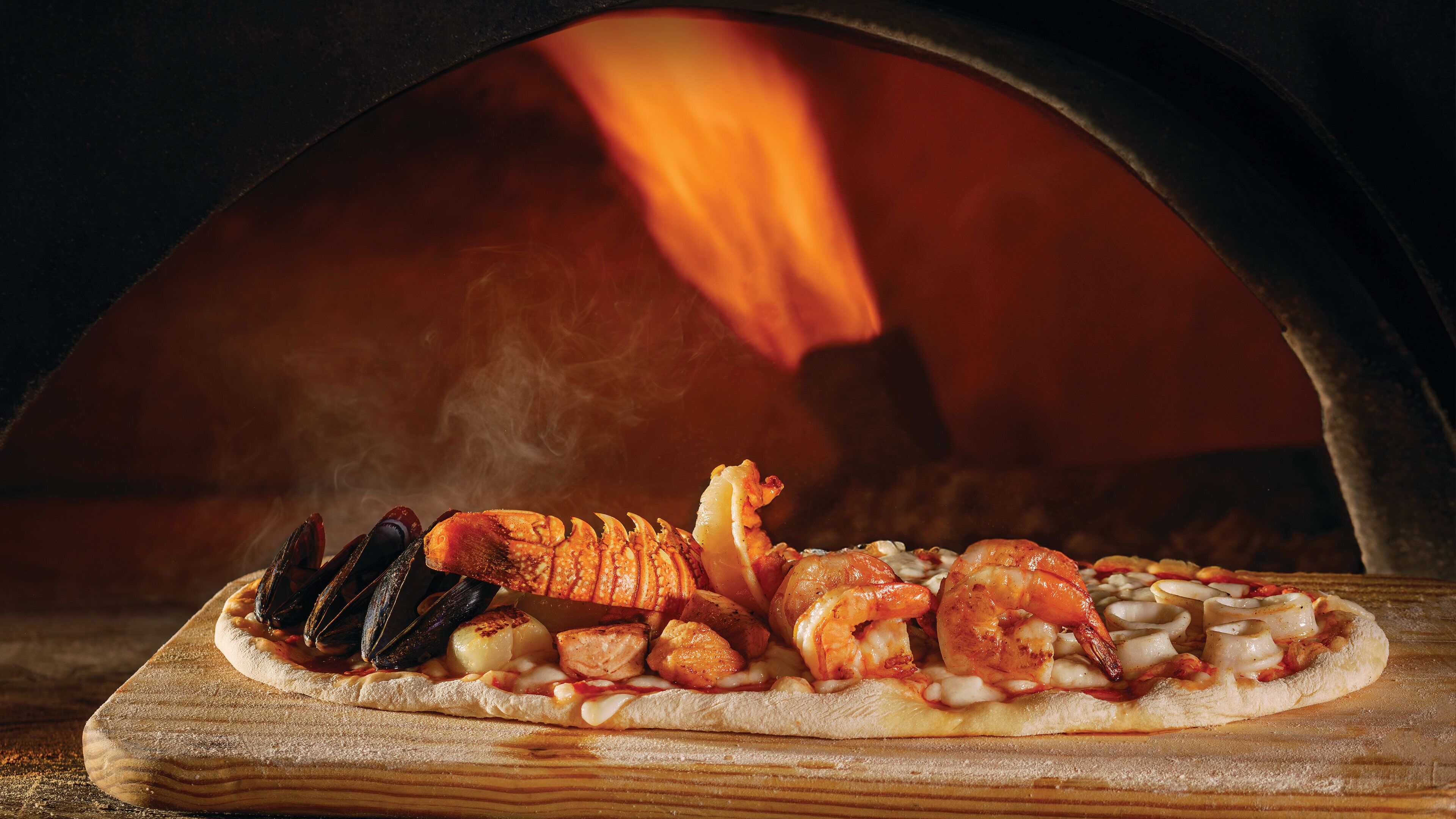 A pizza with seafood toppings in a wood-fired oven.