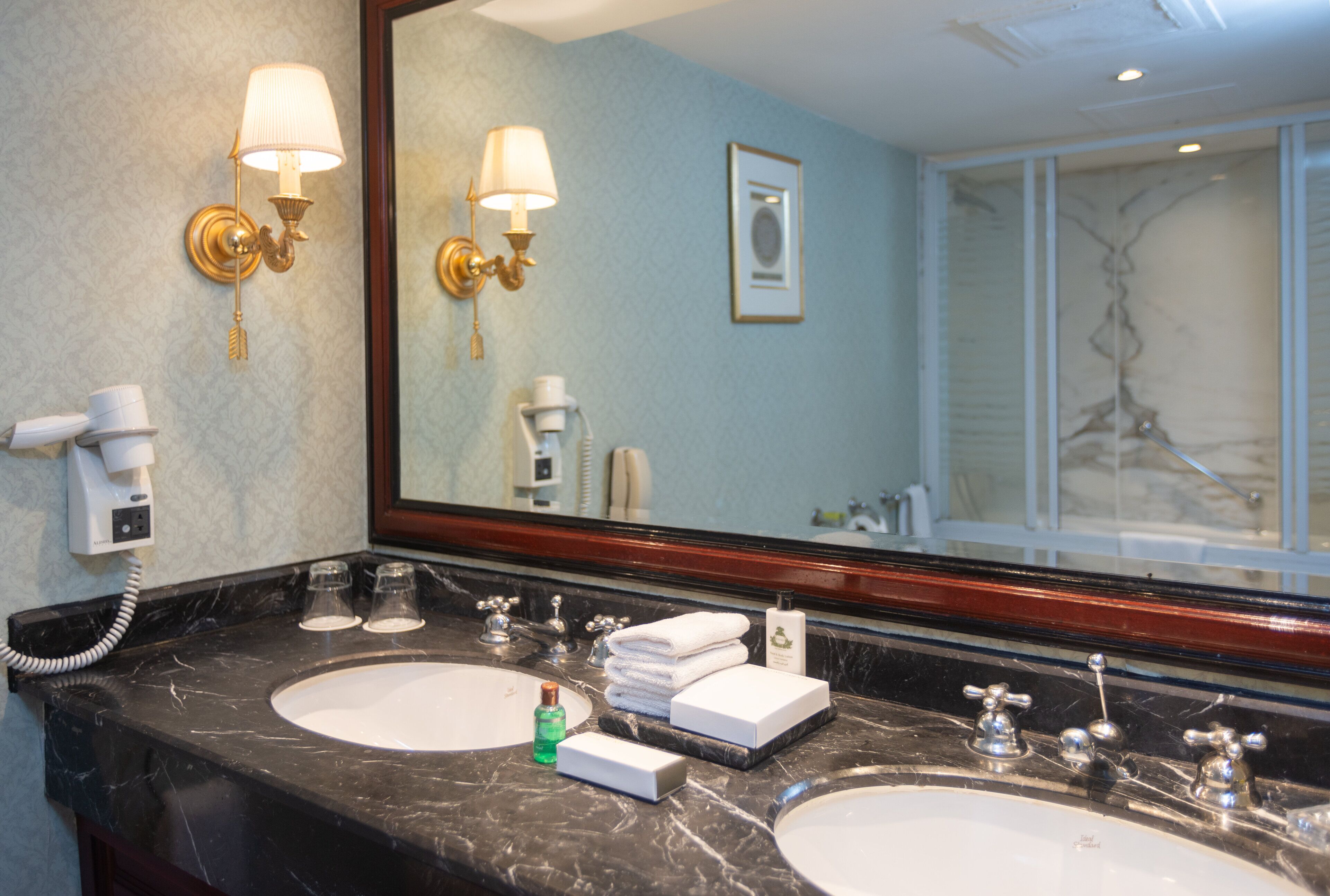 A bathroom with two sinks, a large mirror, and a hairdryer on the wall.