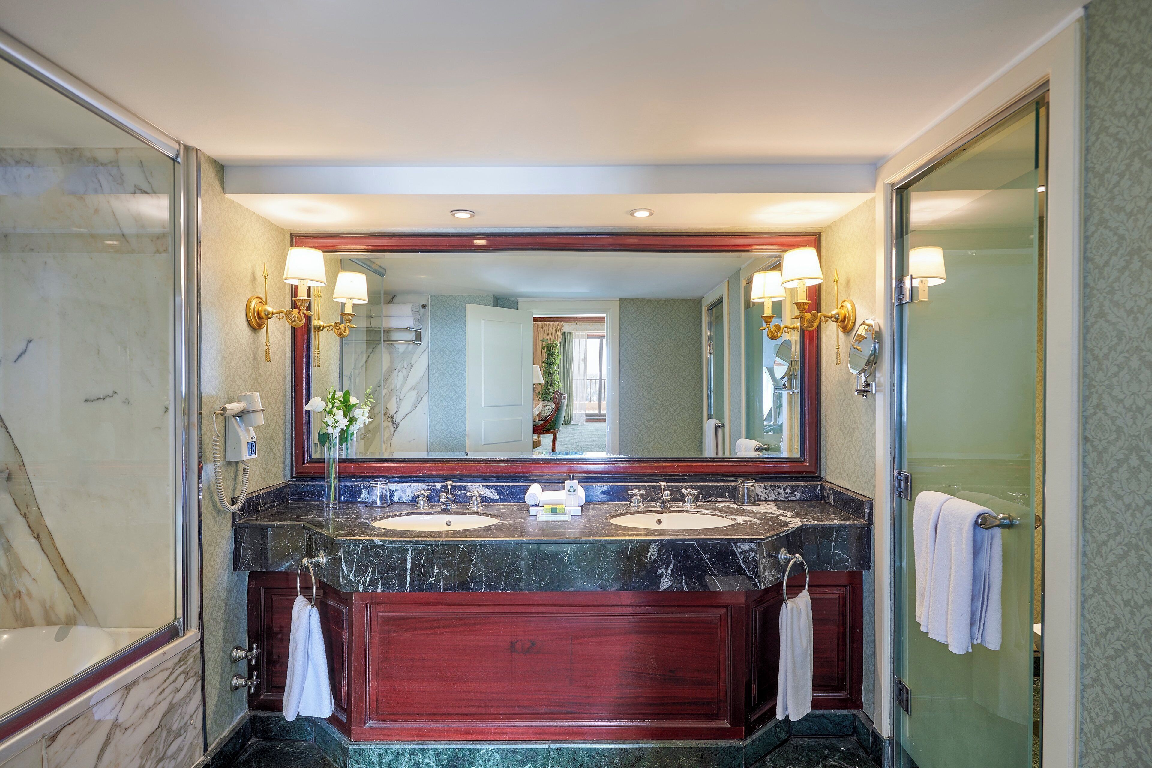 A bathroom with a large mirror, two sinks, and a bathtub.