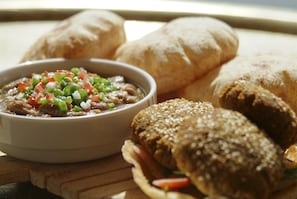 A meal consisting of a bowl of stew with vegetables, two sandwiches, and three pieces of bread.