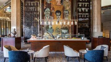 Vestíbulo con zona de bar, asientos y un mural decorativo.