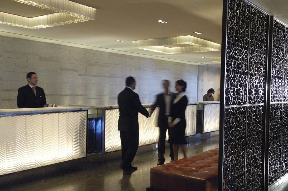 A reception area with a modern design, featuring a reception desk, a seating area, and a decorative wall.