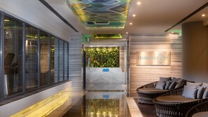 Un espace d’accueil moderne pour un spa, comprenant un comptoir d’accueil, une enseigne et des sièges en osier.