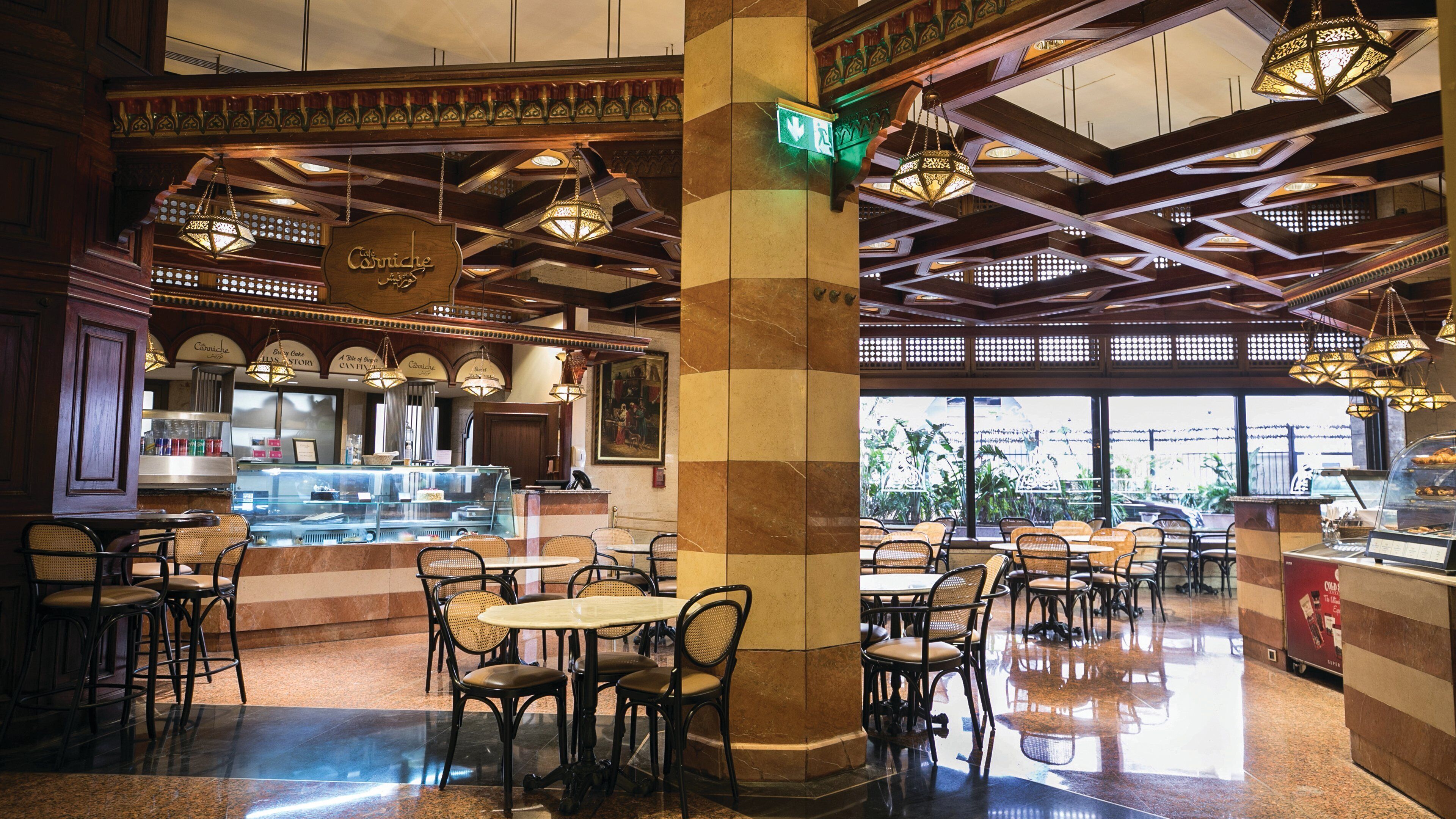 A café with a traditional interior, featuring exposed wooden beams, hanging lanterns, and a central column.