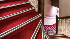 A staircase with red carpeted steps and white balusters. - D'win Hotel (Paris)
