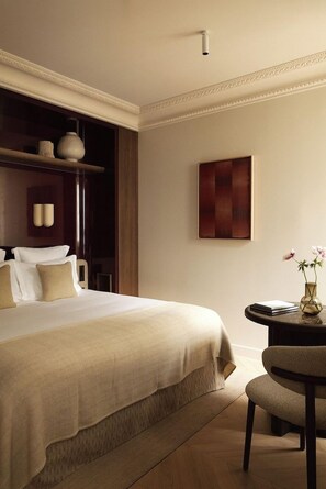 A hotel room with a large bed, a bedside table with a vase of flowers, and a wall-mounted artwork.