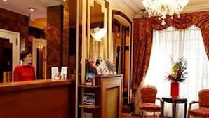 A hotel lobby with a reception desk, a chandelier, and a seating area with chairs. - La Boetie (PARIS)
