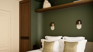 A hotel room with a large bed, two wall-mounted lamps, a wooden shelf, and a wardrobe. - La Boetie (PARIS)