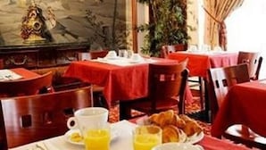 A dining area with tables set for breakfast, including plates of food, cups, and a painting on the wall. - La Boetie (PARIS)