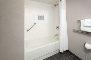Un baño moderno con bañera, cortina de ducha, toallero y artículos de aseo en la pared.