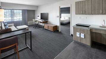 Ett modernt hotellrum med skrivbord, stol och ett litet kök.