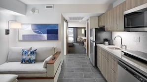 Una habitación de hotel moderna con sofá, comedor y kitchenette.