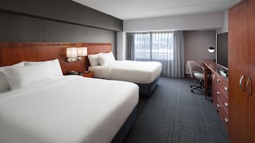 Habitación de hotel con dos camas, un escritorio, un televisor y un armario.