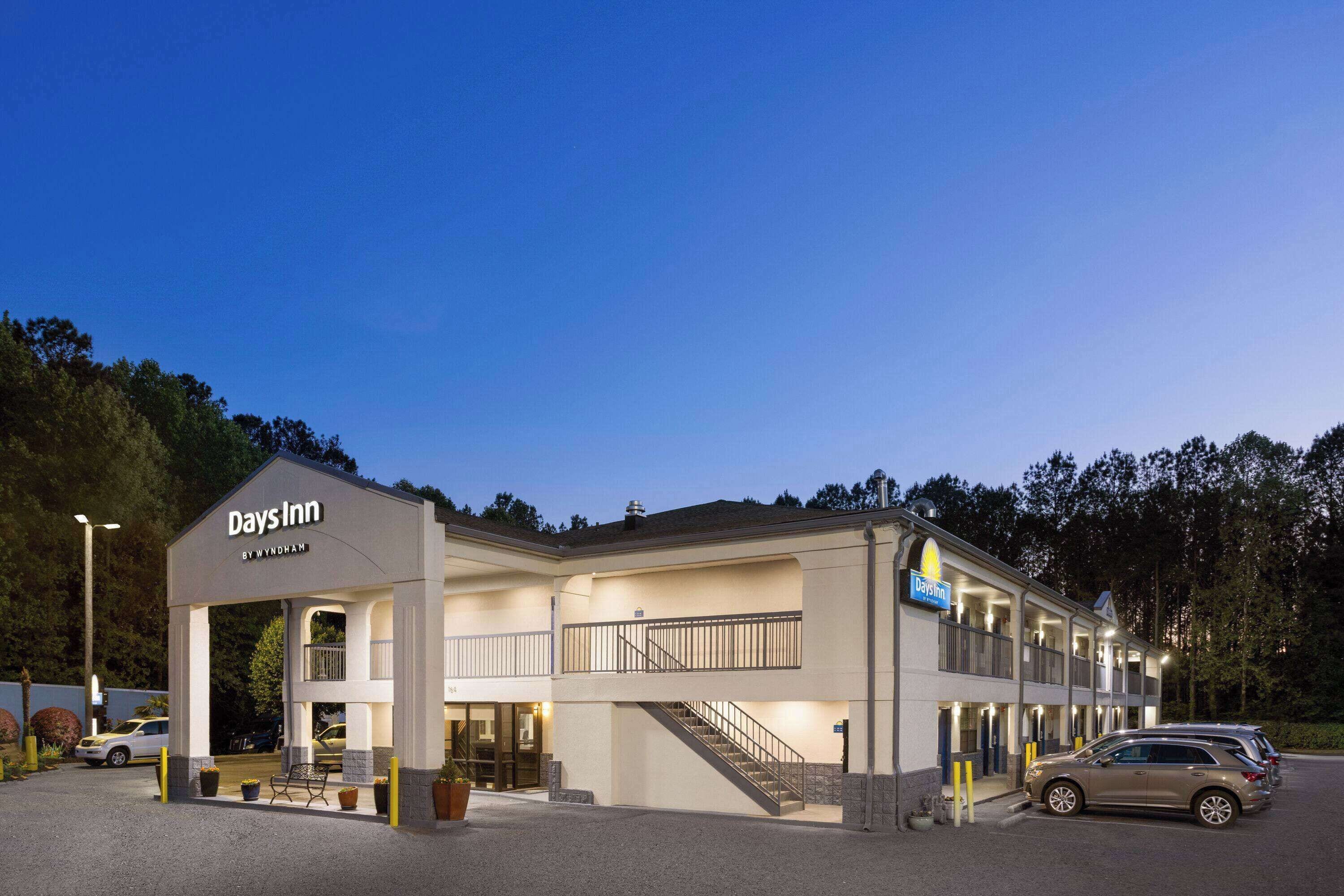 Un hotel Days Inn by Wyndham de dos pisos, con una zona de estar al aire libre cubierta y un estacionamiento.