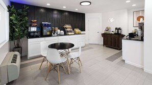 A modern kitchen with a central island, white chairs, a coffee station, and a potted plant. - Days Inn by Wyndham Acworth (Acworth)