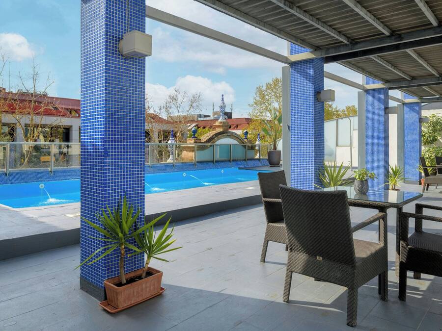 A covered outdoor area with a pool, wicker furniture, and potted plants.