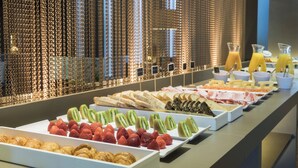 Een ontbijtbuffet met diverse lekkernijen, zoals gebak, fruit en drankjes.