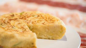 Primer pla d'un plat amb una crosta daurada, possiblement una forta de patates o truita, sobre un plat blanc.