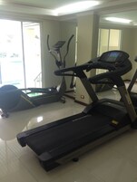 Un gimnasio con cintas de correr, una bicicleta estática y una máquina de remo.