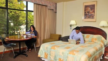 Una camera d'albergo con un letto grande, un tavolo rotondo e una finestra con tende.