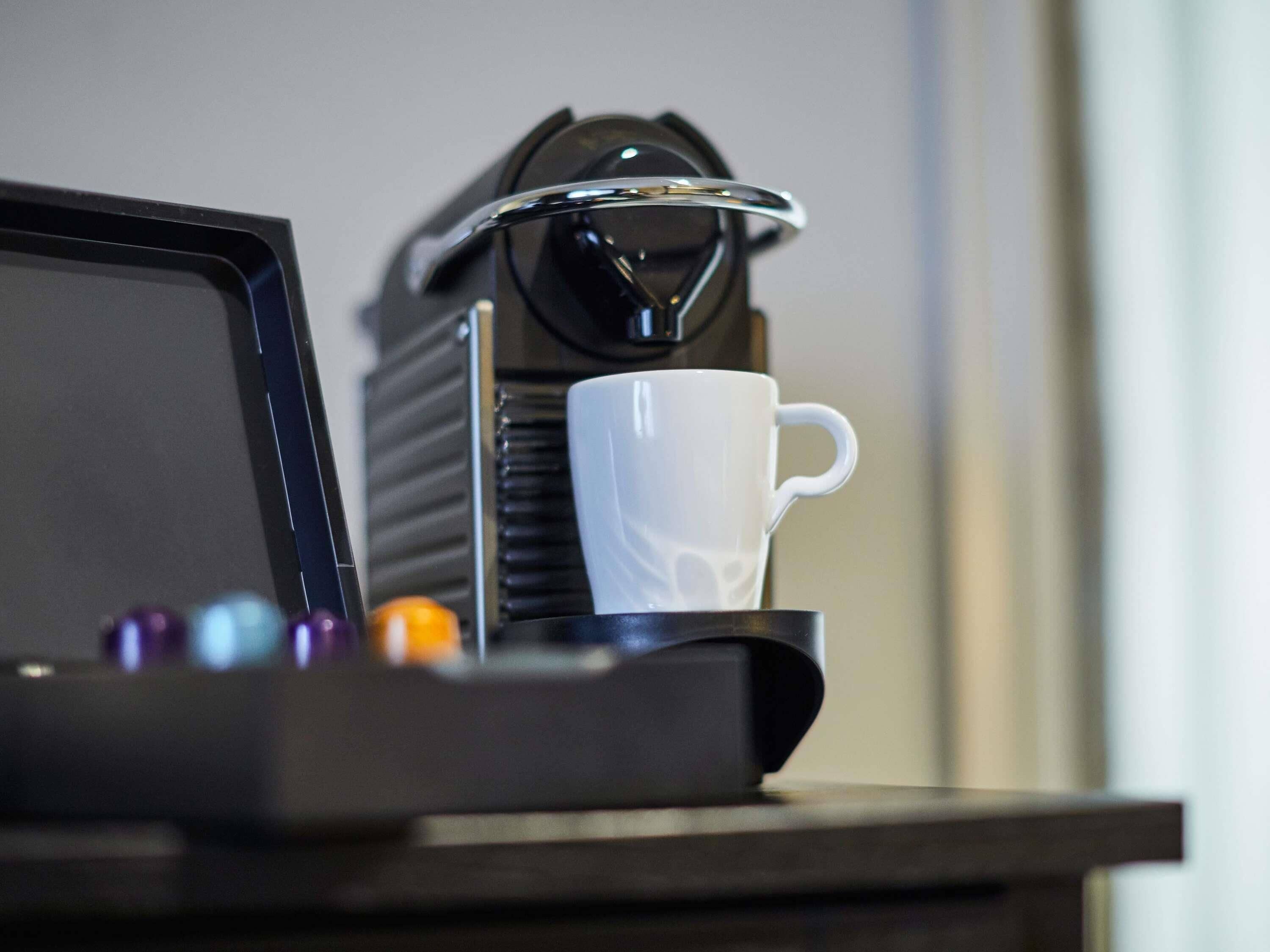 A coffee machine with a white cup on a tray.