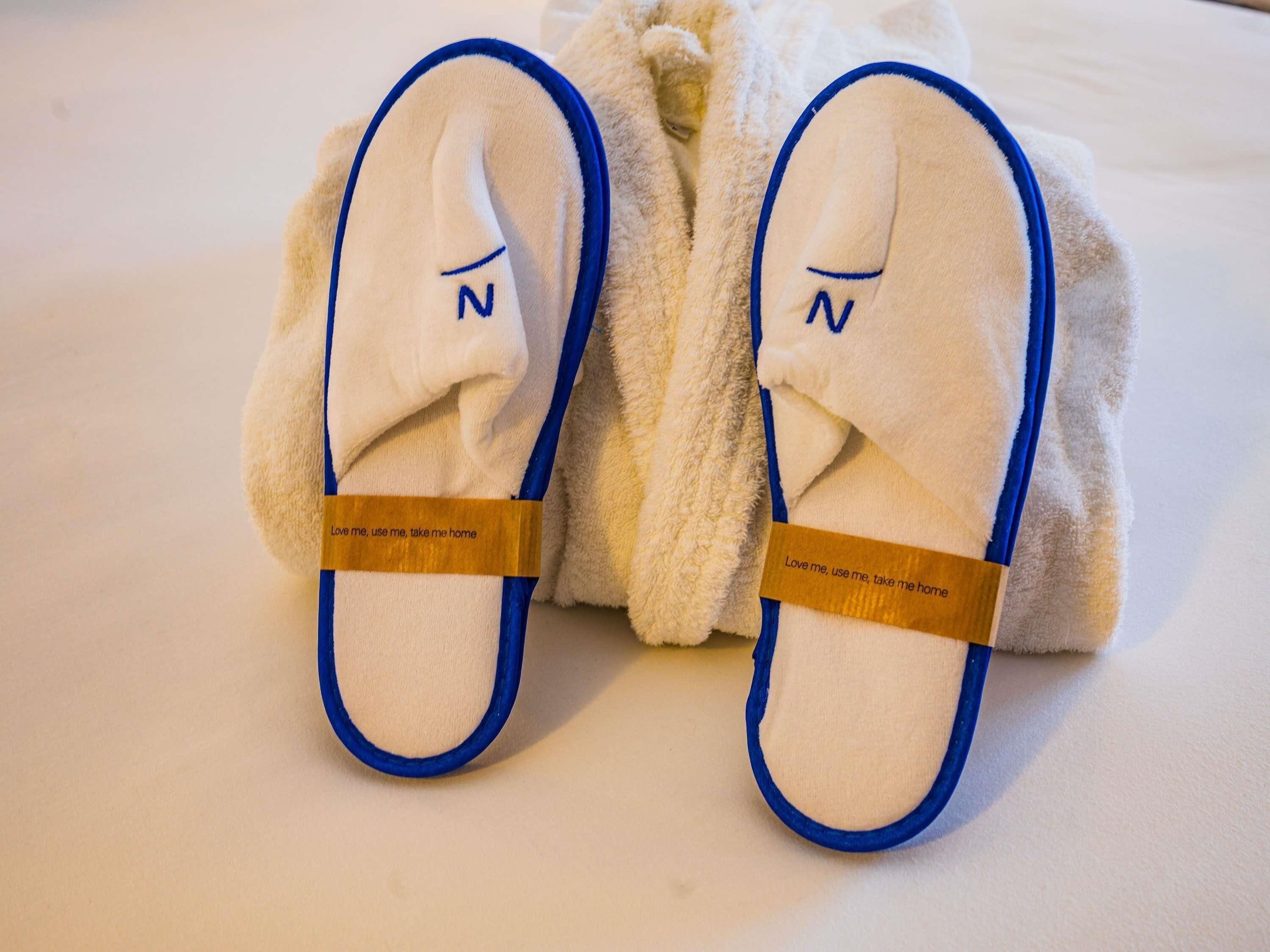 A pair of slippers with a blue trim and a tag that reads 'Love me, use me, take me home.'
