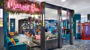 Uma área de bar com um letreiro de neon, assentos e um telefone público vermelho.