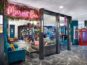 Eine Bar mit einer Neonreklame, Sitzgelegenheiten und einer roten Telefonzelle.