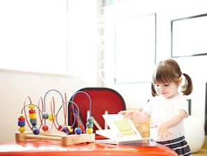 A child playing with an abacus and a book on a red table. - Novotel London West (London)