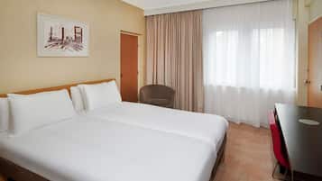 Habitación de hotel con una cama grande, una silla, un escritorio y una ventana con cortinas.