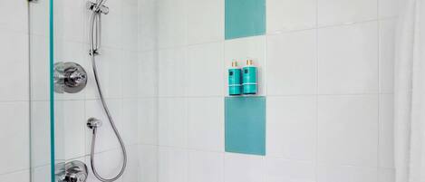 Un baño moderno con cabina de ducha de vidrio, una bañera y un estante con artículos de aseo.