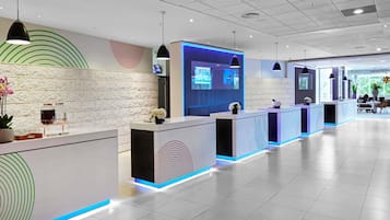 Una moderna zona de recepción con varios mostradores, una pared de piedra y una pantalla grande que muestra información.